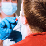 Ein Arzt testet ein Kind mit einem Nasenabstrich.
