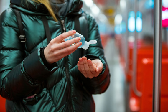 Eine Frau in einer Winterjacke desinfiziert ihre Hände.