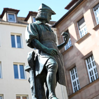 Peter Henlein gilt als Erfinder der Taschenuhr. Sein Standbild thront seit 1905 auf dem Hefnersplatz. Gestiftet wurde der Brunnen von der Stadt und dem deutschen Uhrmacherbund.