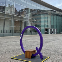 Eine violette Sitzgelegenheit in Form des Buchstabens Q steht auf dem Klarissenplatz vor dem Neuen Museum Nürnberg.