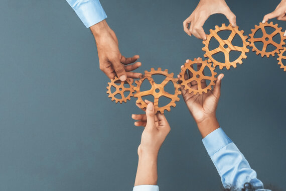 Panoramic shot top view of business people holding cog wheel as unity and teamwork in corporate workplace concept. Office worker colleague with symbol of visionary system for business success. Concord