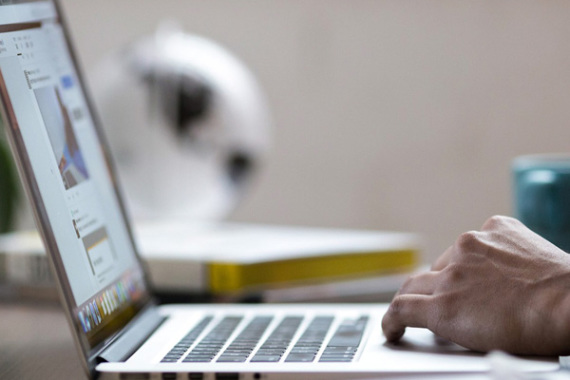 Ein Mann sitzt an seinem Laptop am Schreibtisch.