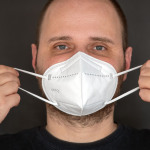 Mann zieht sich FFP2 Maske gegen das Coronavirus an- FFP2 Masken