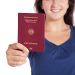 Eine lächelnde junge Frau hält einen deutschen Reisepass in die Kamera.