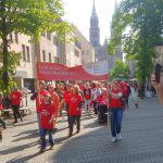 Menschen in roten T-Shirts tragen ein Banner "Inklusion ist MenschenRecht" vor der Lorenzkirche.