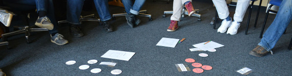 Bunte, beschriftete Karten liegen auf dem Boden, um die Seminarteilnehmer in einem Stuhlkreis sitzen.