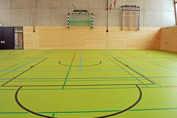 Eine neue Schulsporthalle mit grünem Boden.