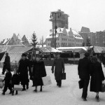 1950: Besucher mit Einkaufstaschen eilen über den verschneiten Markt.