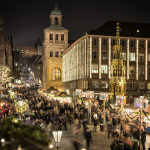 Blick die Burgstraße hinauf. Menschen strömen am Abend im Dunkeln zu den beleuchteten Buden des Nürnberger Christkindlesmarkts.