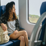 Eine junge Frau sitzt in einem fahrenden Zug.