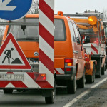 Fahrzeuge mit Warnhinweis-Schildern bei Straßenbauarbeiten