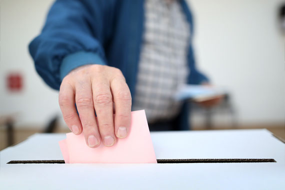 Ein Mann steckt einen Wahlschein in eine Wahlurne