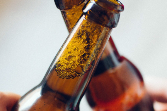 Zwei Menschen stoßen mit Bierflaschen an.