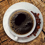 Eine Tasse Kaffee mit Kaffeebohnen auf der Untertasse.