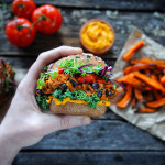 Eine Hand hält einen veganen Süßkartoffel-Bohnen-Burger.