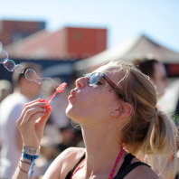 Festivalbesucherin pustet Seifenblasen in die Luft.