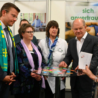 ( Bild: Christine Dierenbach / Stadt Nürnberg ) Bundeskanzler Olaf Scholz (2.v.r.) bei einem Rundgang mit Oberbürgermeister Marcus König (links) auf dem 38. Kirchentag.