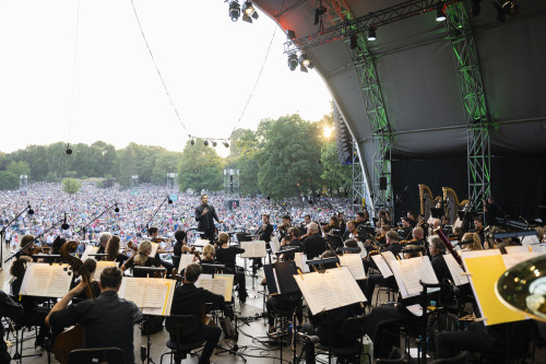 Musiker der Staatsphilharmonie Nürnberg auf der Bühne im Luitpoldhain. Im Hintergrund tausende Zuschauer.