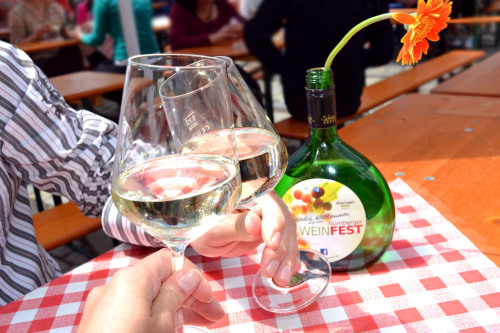 Zwei Gäste stoßen mit Weißwein auf dem Nürnberger Weinfest an.