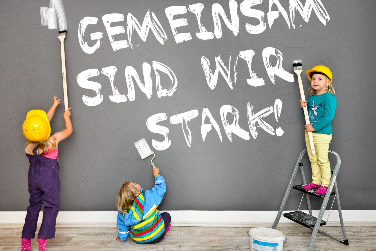 Bild © ©Marco2811 - stock.adobe.com drei Kinder malen schreiben einen Spruch: gemeinsam sind wir Stark an die Wand, Bild © ©Marco2811 - stock.adobe.com