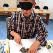 Ein Junge malt mit Augenbinde ein Bild.