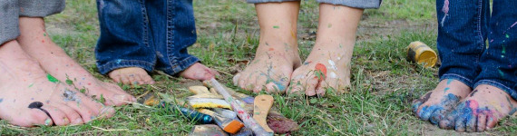 Nackte mit Farbe besprenkete Füße einer vierköpfigen Familie auf einem Rasen.