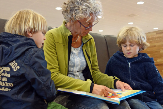 Eine Frau liest zwei Kindern aus einem Buch vor.