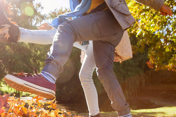 Zwei Teenager toben im Herbstlaub.