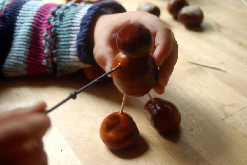 Zwei Kinderhände basteln an einem Kastanienmännchen, Bild © thingamajiggs - stock.adobe.com