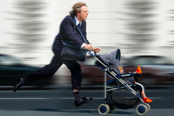 Berufstätiger Mann mit Kinderwagen im Stress
