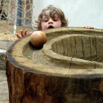 Kind lässt Ball über eine Holzbahn rollen