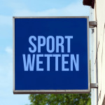 Nasenschild mit der Aufschrift "Sportwetten" an einer Hauswand.