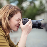Eine Frau fotografiert in der Stadt mit einer Digitalkamera.
