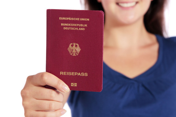 Foto von einer lächelnden junge Frau. Die Frau hält einen deutschen Reise·pass in der Hand.