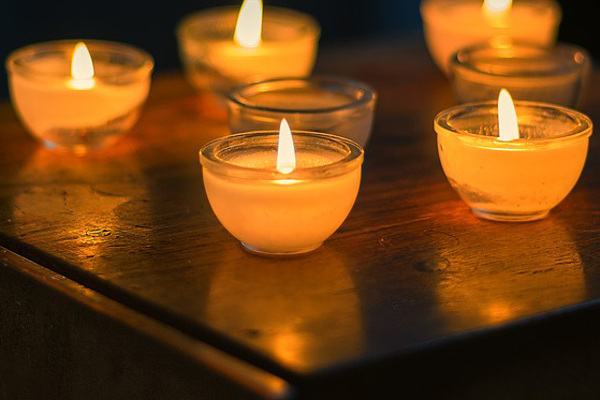 Eine Gruppe kleiner Kerzen in einem dunklem Raum.