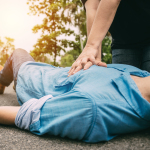 Ein Mann liegt am Boden und wird von einer anderen Person reanimiert.