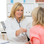 Eine Hausärztin hört eine Patientin mit Stethoskop ab.
