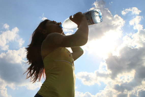 Eine Frau trinkt bei sommerlichem Wetter aus einer Wasserflasche.