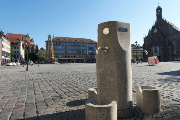 Blick auf den Trinkwasserbrunnen auf dem Hauptmarkt. Im Hintergrund sind der Hauptmarkt und die Frauenkirche zu sehen.