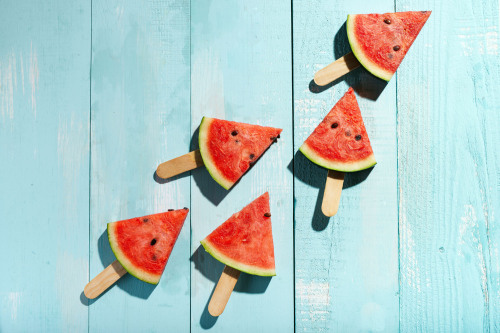 Wassermelonenstücke auf einer hellblau gestrichenem Holzdeck.