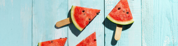 Wassermelonenstücke auf einer hellblau gestrichenem Holzdeck.