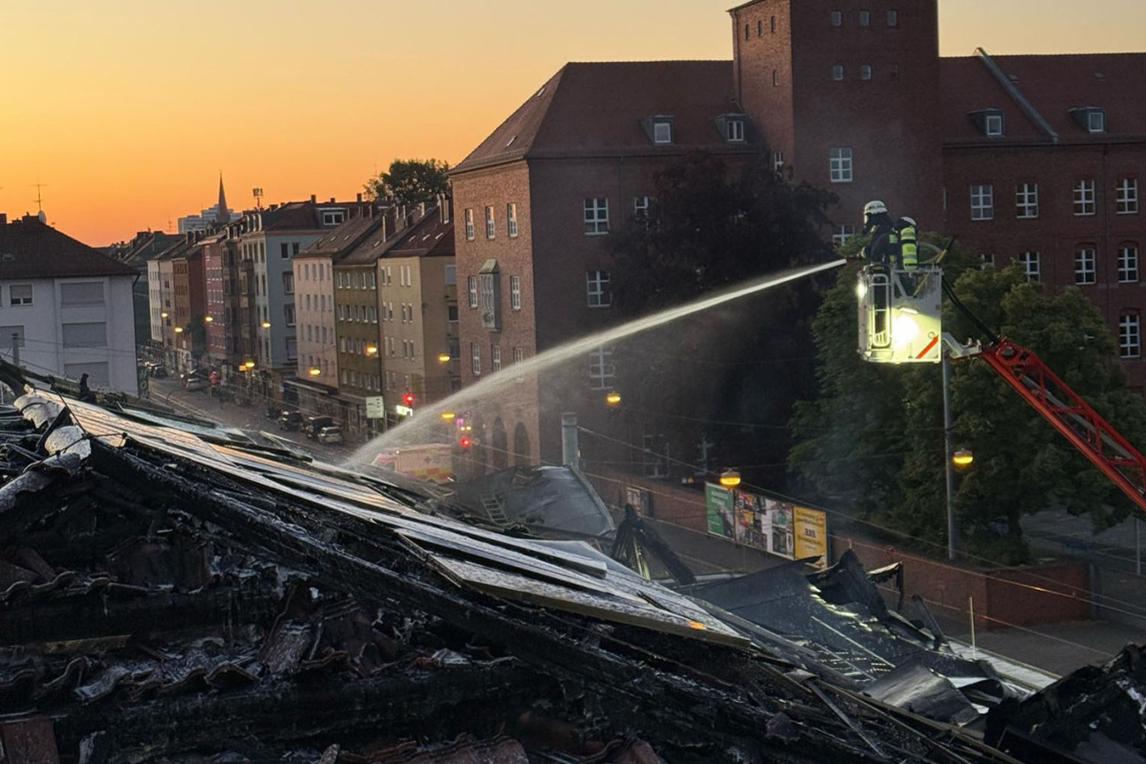 Bild © Feuerwehr Nürnberg Ein Feuerwehrmann auf einer Leiter löscht den Brand im Dach der Turnhalle der Wiesenschule., Bild © Feuerwehr Nürnberg
