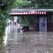 Ein Auto steckt in einer überfluteten Unterführung fest.