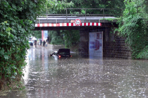 Ein Auto steckt in einer überfluteten Unterführung fest.