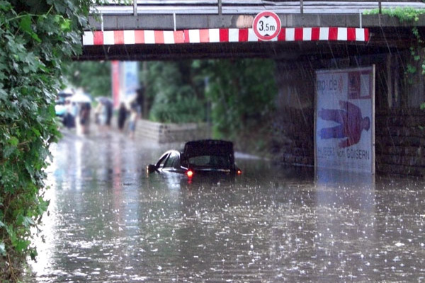 Ein Auto steckt in einer überfluteten Unterführung fest.