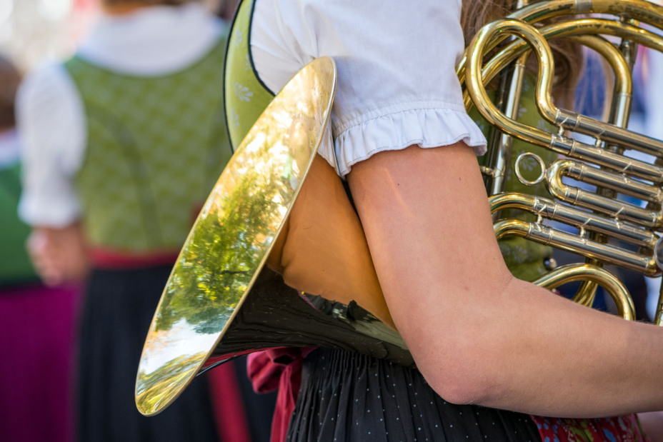 Eine Musikantin im Dirndl mit Horn auf einer Kirchweih.