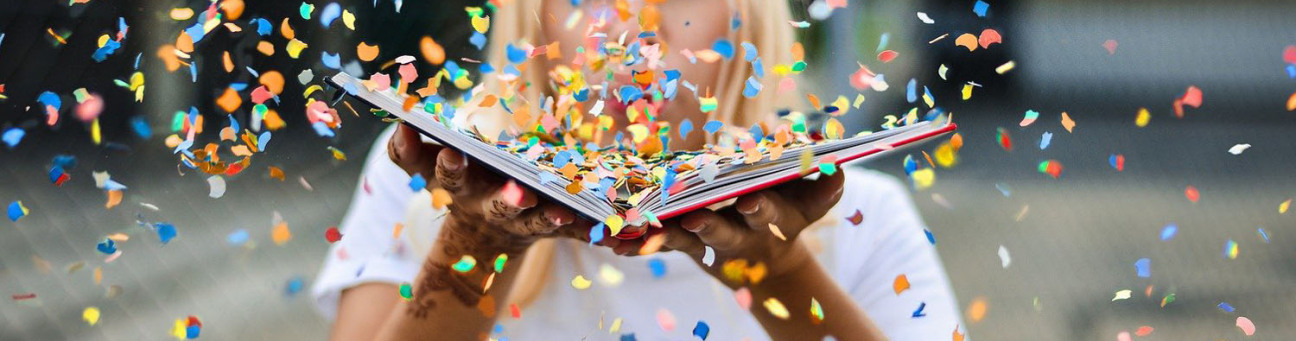 Eine Frau pustet Konfetti aus einem Buch in Richtung Kamera., Bild © Pixabay