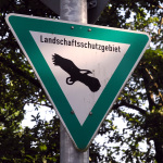 Ein Schild mit einem Adler auf weißem Grund weist ein Landschaf