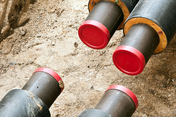 Offengelegte Fernwärme-Rohre in einer Baugrube.