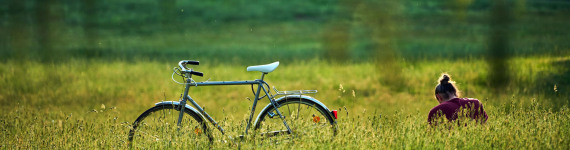 Radfahrerin sitzt neben ihrem agestellten Fahrrad in einer Wiese im Pegnitztal.